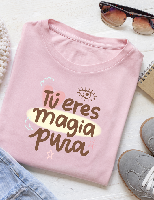 Pink t-shirt with 'Tu eres magia pura' text on a white surface with sunglasses and shoes.