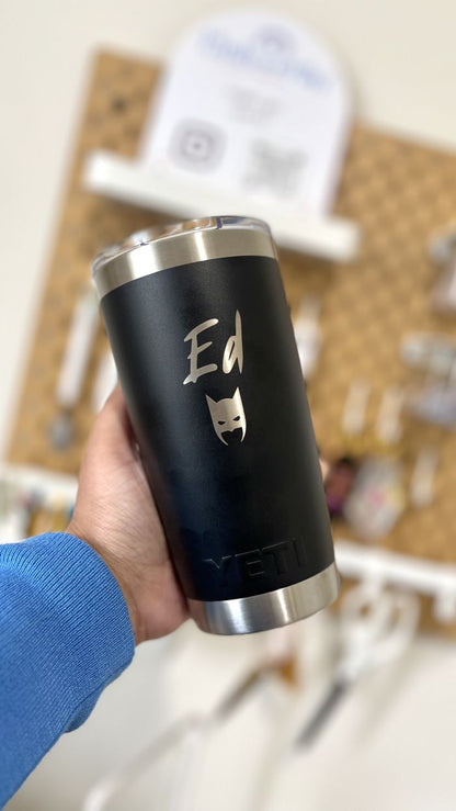 Black tumbler with 'Ed' and a cat illustration held by a person in a blue sleeve.