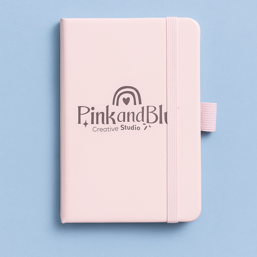 Pink notebook with 'Pink and Blk Creative Studio' logo on a light blue background
