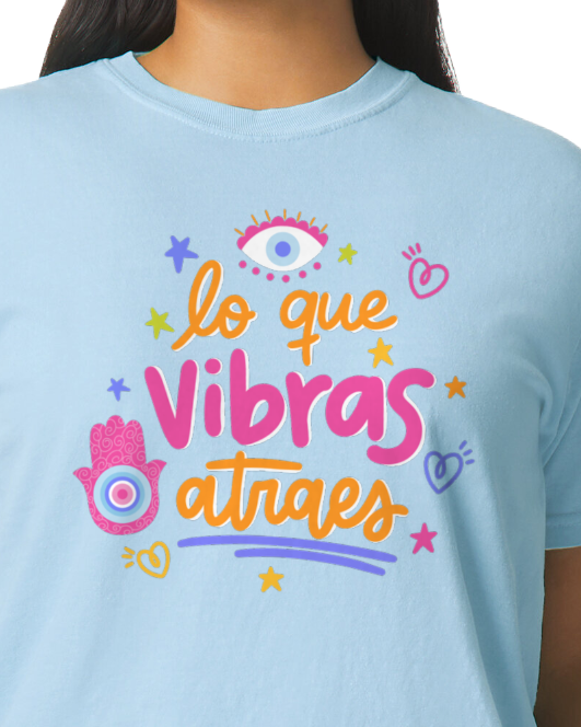 Light bluet-shirt with orange and pink text and graphics on a plain background