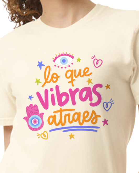 Beige t-shirt with orange and pink text and graphics on a plain background