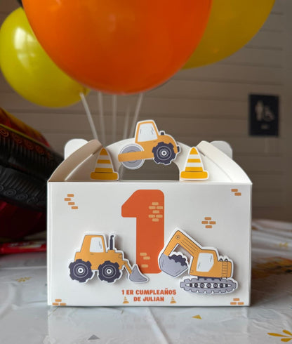 Children's birthday party favor box with construction theme and balloons in the background