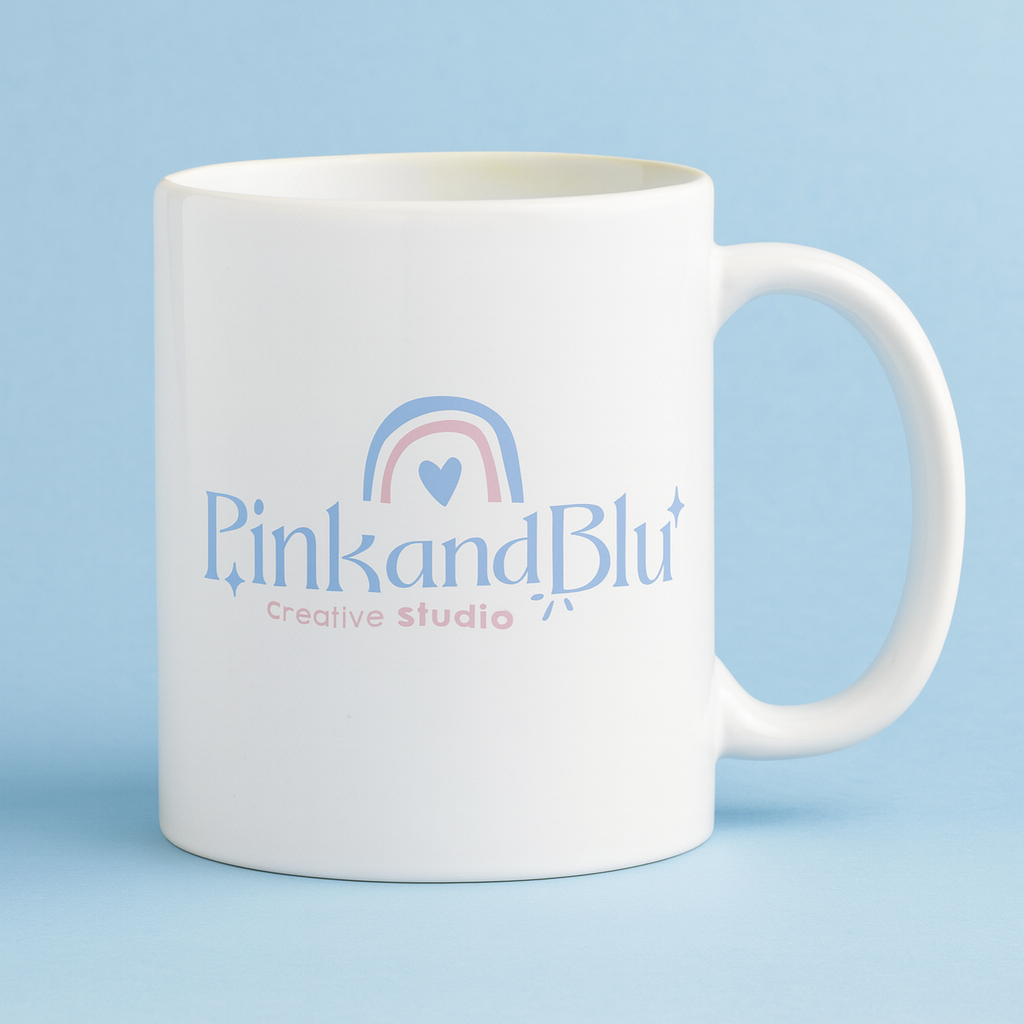 White mug with 'Pink and Blu Creative Studio' logo on a light blue background