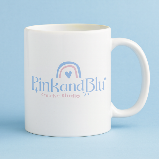 White mug with 'Pink and Blu Creative Studio' logo on a light blue background