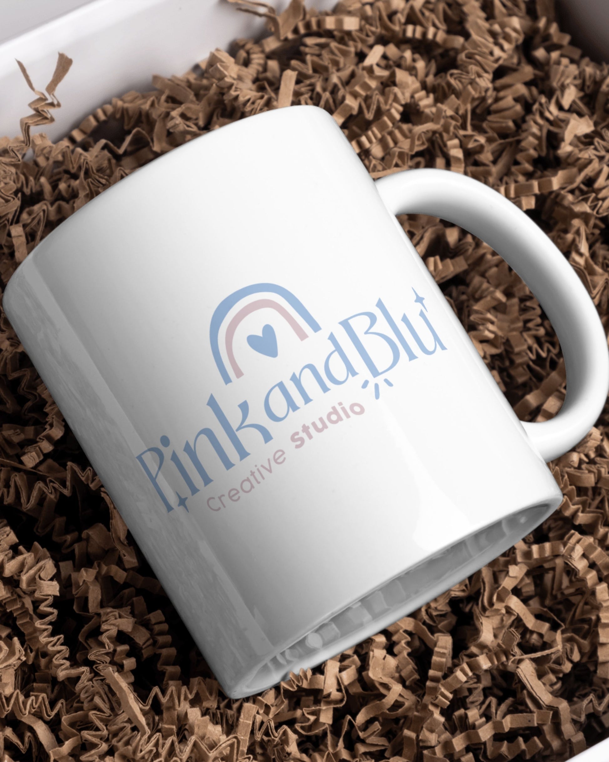 White mug with 'Pink and Blu' logo on brown crinkled paper