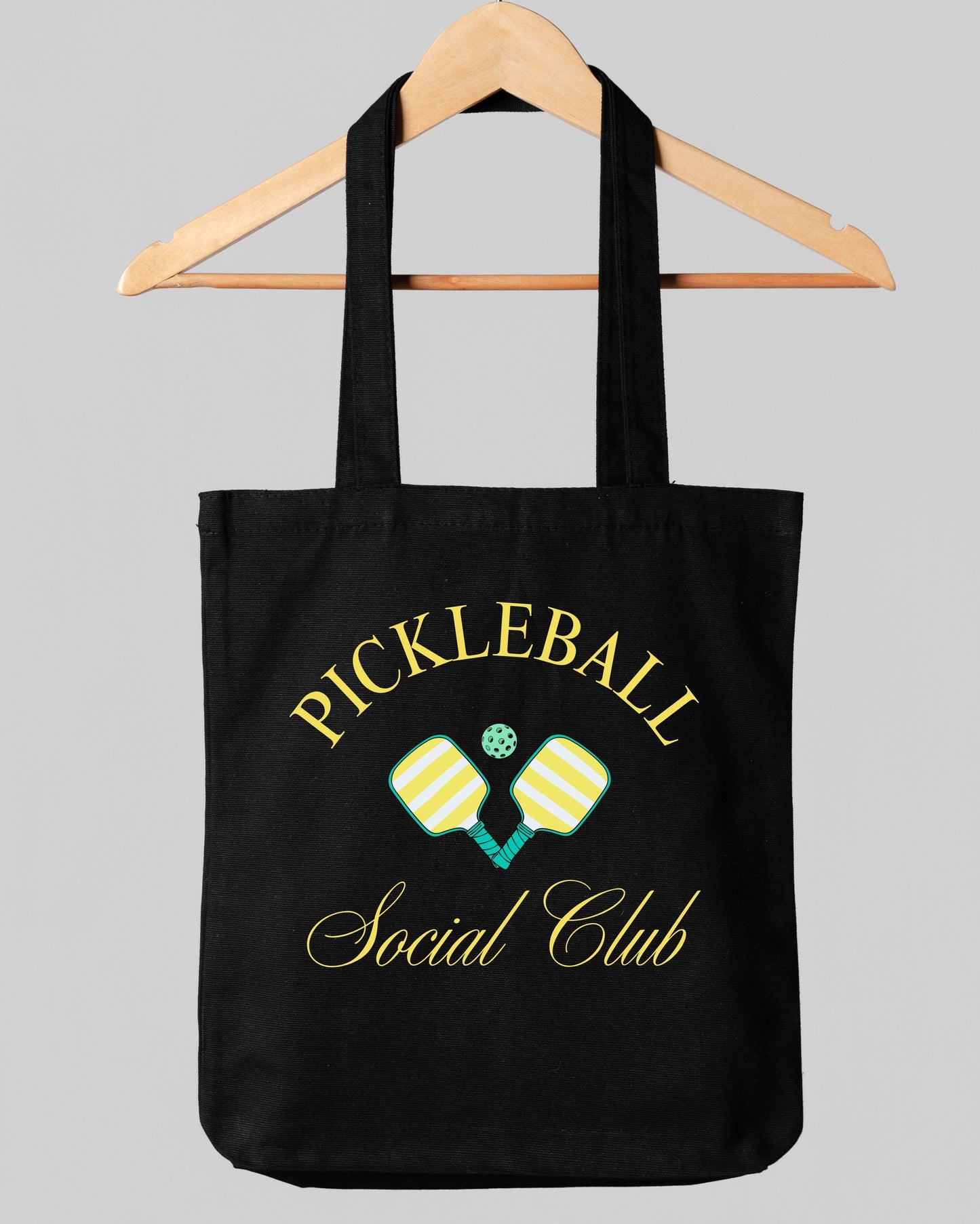 Black tote bag with 'Pickleball Social Club' text and pickleball paddle design on a gray background