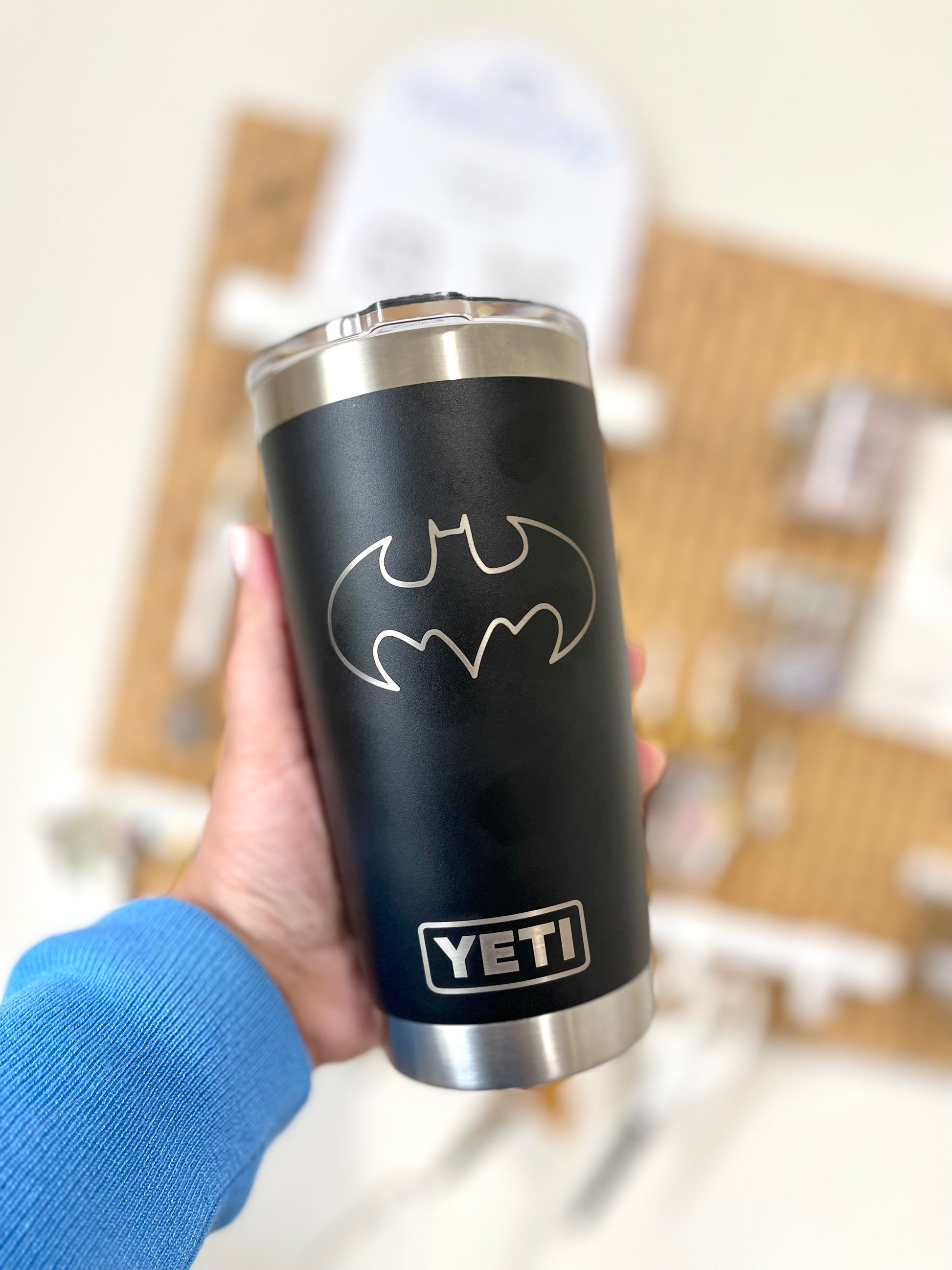 Black YETI mug with Batman logo held by a person wearing a blue sleeve.